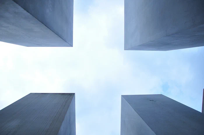 Worm's-eye view of four concrete pillars against a cloudy sky.